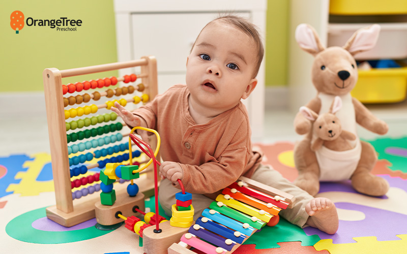 Baby playing with educational toys on colorful mat.