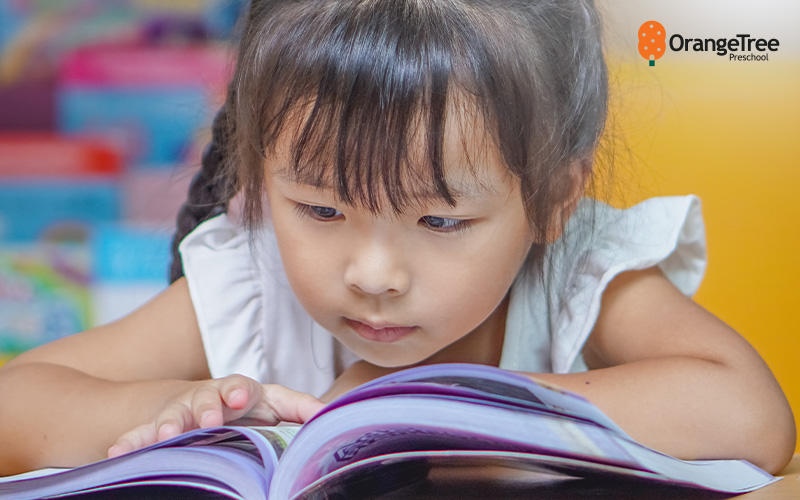 Child reading a book at OrangeTree Preschool.