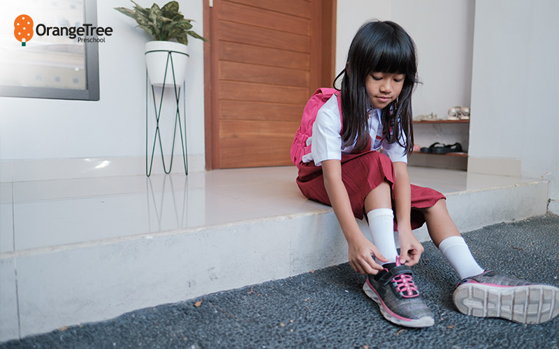Child tying shoes, preparing for primary school.