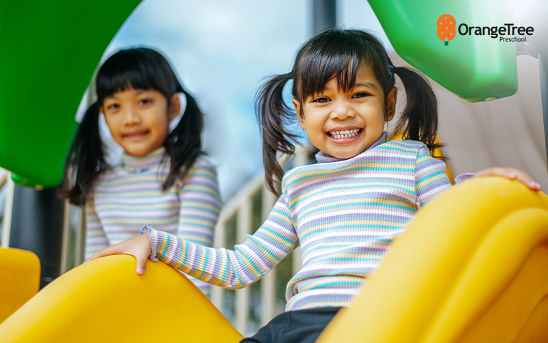 Happy children playing on a slide at OrangeTree Preschool.