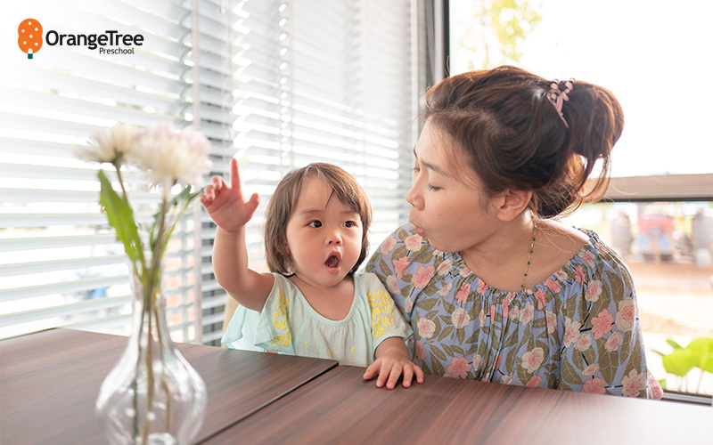 Mother and child pointing at a flower.