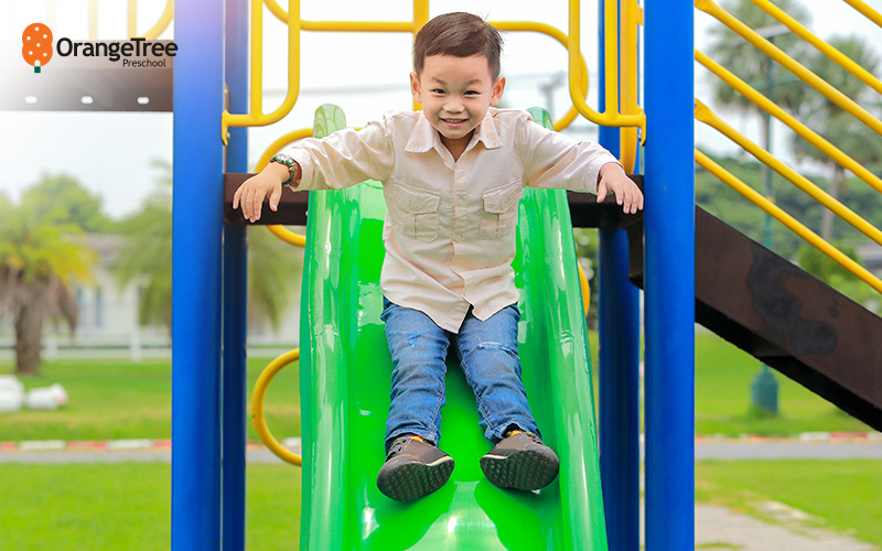 OrangeTree Preschool child enjoying slide at playground.