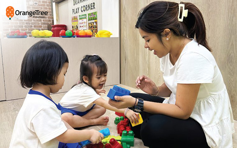 OrangeTree Preschool teacher playing with children.
