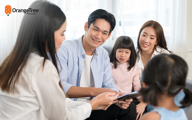 Parents discussing preschool learning with a teacher.