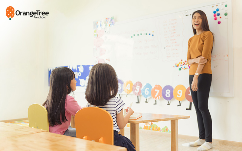 Preschool teacher engaging with young students.