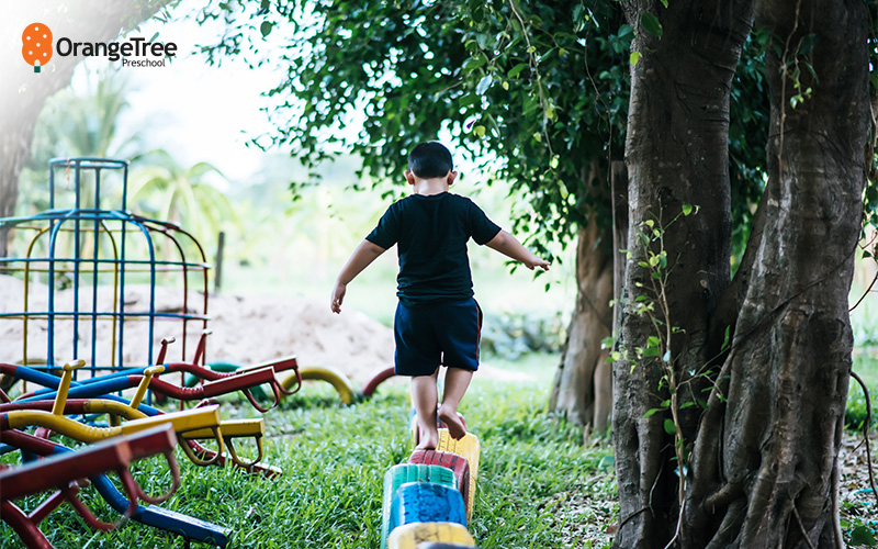 Preschooler balancing on outdoor play equipment.