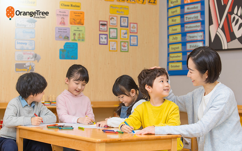 Teacher encouraging kids during classroom coloring activity.