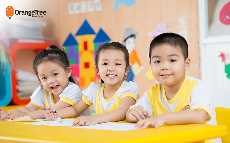 Three OrangeTree preschoolers drawing happily in class.