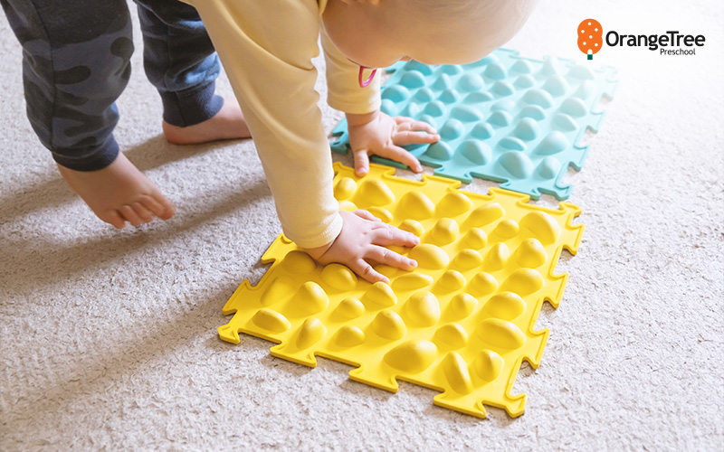 Toddler_playing_on_sensory_mats_for_development Toddler playing on sensory mats for development.