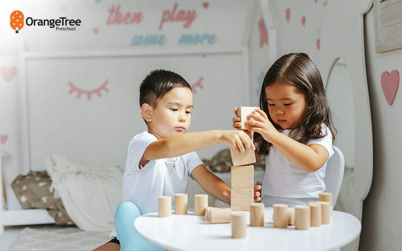 Two children playing with wooden building blocks.