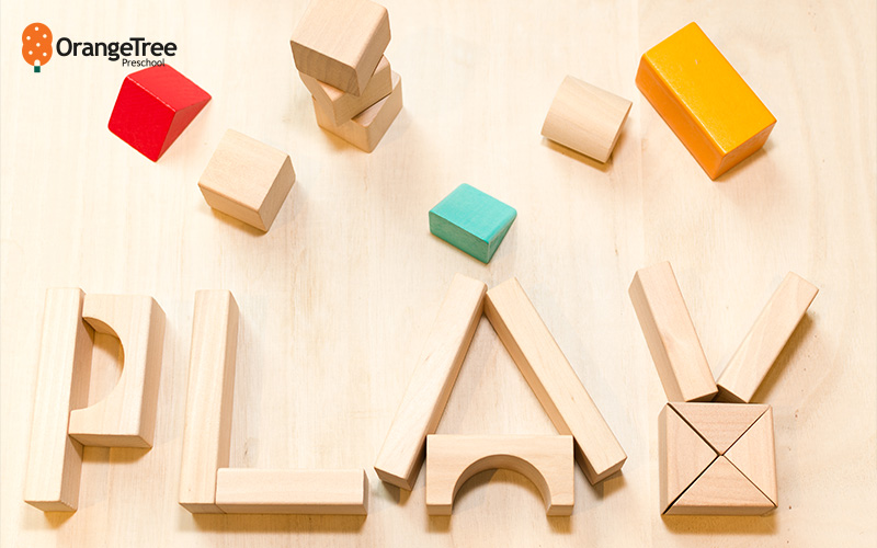 Wooden blocks spelling "PLAY" on a table.
