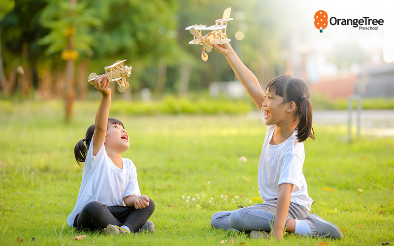 children playing with wooden planes outdoors